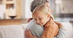 Love, sweet and grandmother hugging her grandchild while relaxing in the living room of a home. Happy, smile and senior woman embracing a little girl kid with care on sofa in the lounge at her house.