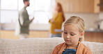 Fear, divorce and parents fighting with a girl sitting on a sofa in the living room of her home during an argument. Sad, stress or anxiety with a daughter watching conflict of her mother and father