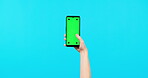 Person, hands and phone mockup for social media, advertising or marketing against a blue studio background. Hand holding mobile smartphone app for advertisement on chromakey with tracking markers