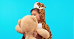 Children, teddy bear and pajamas with a girl at bedtime on a blue background in studio for imagination. Kids, fantasy and a playful young female child in a leopard costume holding a stuffed animal