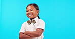 Bow tie, and an indian girl child arms crossed on a blue background isolated in studio for fashion or trendy style. Portrait, children and a happy female kid posing indoor in a stylish outfit