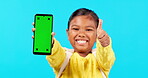 Happy girl, thumbs up and phone on mockup for social media against a blue studio background. Portrait of little child or kid smile with like emoji, yes sign or approval for mobile smartphone app