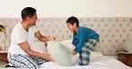 Playful, pillow fight and father and child in the bedroom for bonding, morning fun or playing together. Happy, family and young dad fighting with a kid and pillows on the bed of a house and laughing