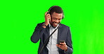 Business man, headphones and phone on a green screen with a smile, music and bag for travel. Black male entrepreneur on a studio background with a smartphone for streaming, dancing and happy
