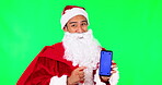 Man, Santa and phone mockup on green screen for Christmas advertising against a studio background. Portrait of male person, festive or Saint Nicholas show mobile smartphone app with tracking markers