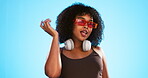 Face wink, sunglasses and hair care of woman in studio isolated on a blue background. Gen z portrait, retro shades and happy female model with salon treatment for beauty and headphones.