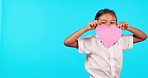 Happy, smile and child with a heart shape paper in a studio for valentines day, celebration or romance. Happiness, excited and portrait of a girl kid model moving with a love sign by blue background.