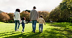 Back, walking and an interracial family at a park for bonding and `care while holding hands. Summer, love and parents with children and affection in nature for a walk, to relax or on a vacation