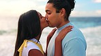 Love, date and a couple kissing on the beach outdoor during summer while on holiday or vacation together. Travel, romance or anniversary with a young man and woman bonding at the coast by the ocean