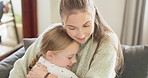 Mom, love and hug girl with a smile or bonding, support and care for child with happiness on living room, sofa or home. Hugging, mother and daughter with happy embrace and quality time together