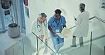Talking, doctor and nurse walking on stairs with documents in hospital lobby. Conversation, medical professional or surgeon on steps in clinic with paperwork for healthcare, teamwork or collaboration