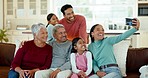 Family, selfie and grandparents with kids on sofa for bonding, quality time and memories in living room. Home, children and mom, dad and senior parents on couch for picture, post and social media