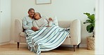 Senior couple, laughing and talking on sofa with home living room blanket in love, relax or communication of joke. Smile, woman or happy elderly man with comedy, funny and humor storytelling on couch