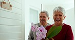 Senior man, woman and front door for welcome, flowers and wine for housewarming gift, party and excited smile. Elderly people, plants and happy for new home, property or real estate with present