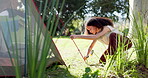 Tent, nature and woman with a setup for a camp in a forest for holiday or adventure. Vacation, outdoor and a young girl with a hammer for shelter in the woods for a break, trekking or gear in morning