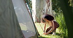 Tent, nature and a woman with a camping setup in a forest for holiday or adventure. Vacation, outdoor and a young girl with a hammer for shelter in the woods for a break, trekking or gear on a camp