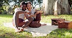 Happy, social media and an interracial couple on a picnic with a phone for communication, tech or an app. Talking, summer and a black man and woman with a mobile for a chat on a date in a park