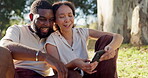 Laughing, social media and an interracial couple on a picnic with a phone for communication, tech or an app. Talking, summer and a black man and woman with a mobile for a chat on a date in a park