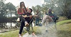 Friends, campfire and guitar with music, relax and conversation in nature, woods or park for vacation. Men, woman and hug with beer, chat and camping by bonfire, art and outdoor in forest for holiday