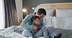 Family, playing and father with boy child in bed happy, tickle and having fun at night in their home. Love, happy and kid with playful parent in a bedroom bonding, laughing and enjoying game together