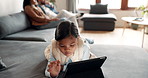 Relax, tablet and child on sofa in home living room, typing or streaming movie, video or cartoon. Technology, girl and kid lying on couch on social media, gaming app or browsing internet in house.