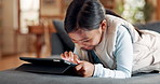 Sofa, tablet and happy kid in home living room, streaming movie or video of cartoon online. Technology, smile and girl child lying on couch to scroll social media, gaming app or browsing internet.