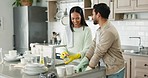 Couple, talking and kitchen sink for washing dishes together, helping hand or happy chat in home with joke. Man, woman and teamwork for bacteria, cleaning or smile for comic conversation in apartment