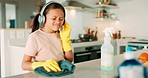 Girl child, headphones and cloth for cleaning, table and dancing with spray, music and happy in family home. Young kid, audio tech and chemical for dirt, bacteria and streaming online radio in house