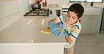 Kitchen counter, learning or child house cleaning with gloves or cloth to wipe a dirty table for wellness. Independence, kid or young boy working on messy bacteria on countertop surface at home alone