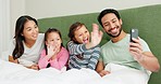 Mother, father and children hello on a video call on bed in a family home for quality time and bonding. A man, woman and girl kids in a bedroom together for online communication or virtual chat