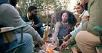 Camping, fire and people with marshmallow in nature for holiday, vacation and adventure in woods. Friendship, travel and happy men and women with snack by bonfire for bonding, quality time and relax 