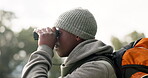 Black man, binoculars and backpack in travel for sightseeing or looking for path and hiking trail in nature. African male person or hiker with vision to explore adventure, sight or journey outdoors