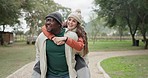 Interracial couple, piggyback and walking in park for bonding, love or care together in the outdoors. Happy man and woman enjoying back ride, scenery or natural environment on weekend holiday outside