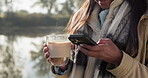 Smartphone, hands and coffee, woman is outdoor camping and typing in chat with travel and warm beverage. Communication, mobile app and female camper in nature, caffeine drink and social media contact