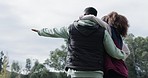 Camping, couple and rear view of hand pointing to forest, view or nature, relax and talking together. Love, woods and behind man with woman at a camp site for freedom, vacation and woods experience