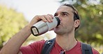 Nature, health and man walking in a park for fresh air with a bottle of water and backpack. Adventure, exercise and young male person for fitness in an outdoor green garden with a positive mindset.
