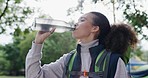 Hiking, freedom and woman drinking water in a forest for hydration while exploring nature. Camping, drink and thirsty female explorer on fitness, break and resting while walking through the woods 