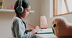 Education, girl with headphones and doing homework, learning with music and study for academic growth at desk. Female kid, writing with pencil and school work, child development and audio streaming