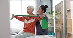 Senior woman doing a exercise with a resistance band for physiotherapy with a nurse in clinic. Fitness, healthcare and elderly female patient doing arm workout with therapist in rehabilitation center