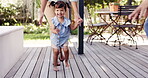 Happy, girl or child learning to walk or dance with parents in outdoor garden, backyard or toddler on the deck of home with family. Mom, dad and excited kid walking, running or dancing with happiness