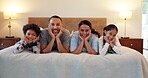 Family, happy together and portrait on a bed with happiness on holiday, vacation or parents with love for children. Mom, dad and kids with smile on face in bedroom or bonding with boy and girl