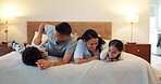 Happy family, bed and fun playing together enjoying holiday weekend, bonding or quality time at home. Father, mother and children laughing in happiness for funny tickle, love or care in bedroom