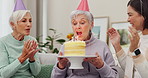 Birthday party, cake or applause with a senior woman blowing out candles with friends in the home living room. Celebration, milestone and clapping with a mature person enjoying a retirement event