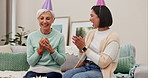 Birthday, party and cake with a senior woman blowing out candles then hugging a friend in the home living room. Celebration, applause and milestone with a mature person enjoying a retirement event