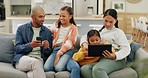 Parents networking with their girl kids on a technology on a sofa in the living room at home. Bonding, love and young mother and father browsing on a cellphone and digital tablet with their children.