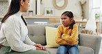 Mother, child and upset at home for discipline, bad behaviour or psychology problem on a sofa. A woman or psychiatrist talking to a angry girl kid in a living room for discussion, advice or support