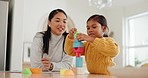 Mother playing with building blocks with her girl kid in the kitchen for child development at home. Happy, bonding and young Asian mom helping her daughter with wood toys for fun at their house.