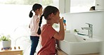 Children brushing their teeth for dental care in the bathroom of their modern family home together. Hygiene, oral health and girl kids doing a clean mouth routine for wellness in their house.