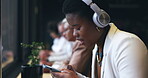 Headphones, phone and woman at cafe listening to music, remote work and networking on social media. African person in workspace, restaurant or coffee shop with mobile chat and audio streaming service