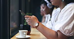 Coffee shop, phone and woman typing on social media, networking or marketing communication by window. Creative person or entrepreneur at restaurant or cafe for remote work, workspace and mobile chat